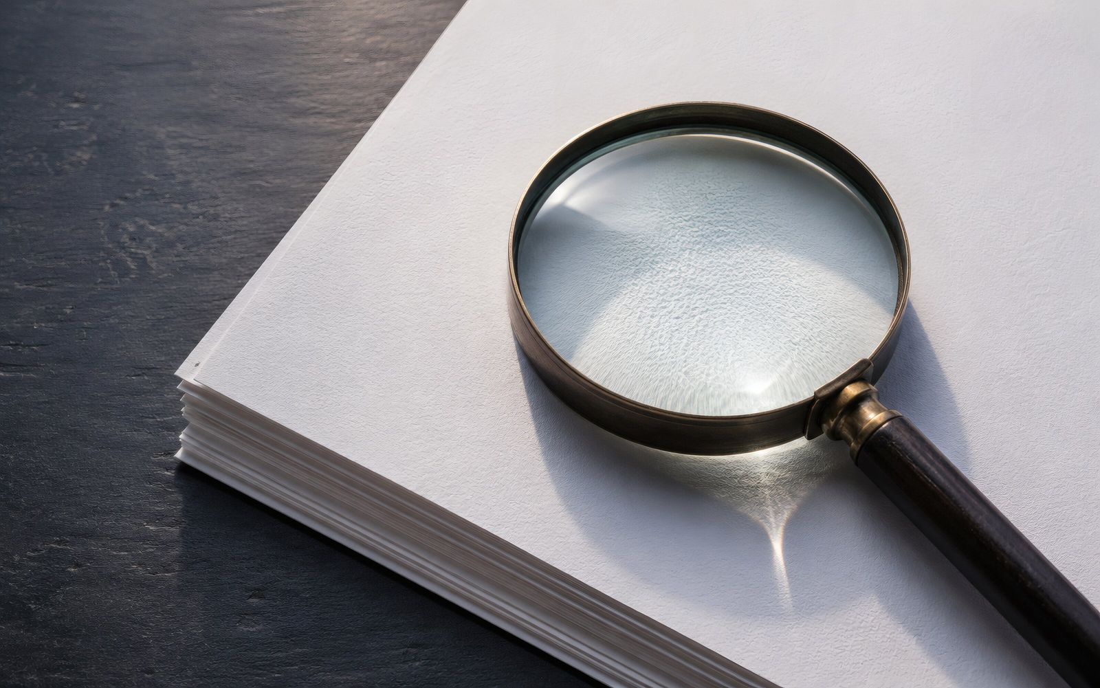 Magnifying glass resting on a stack of documents